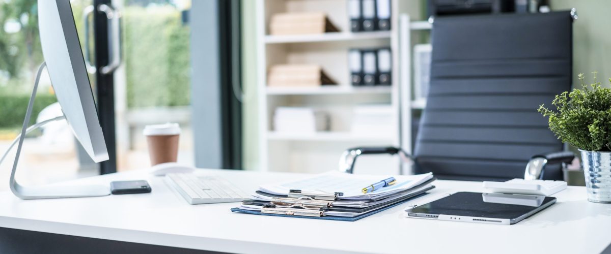 A desk in the office is neatly organized  a computer monitor, document, tablet, telephone placed