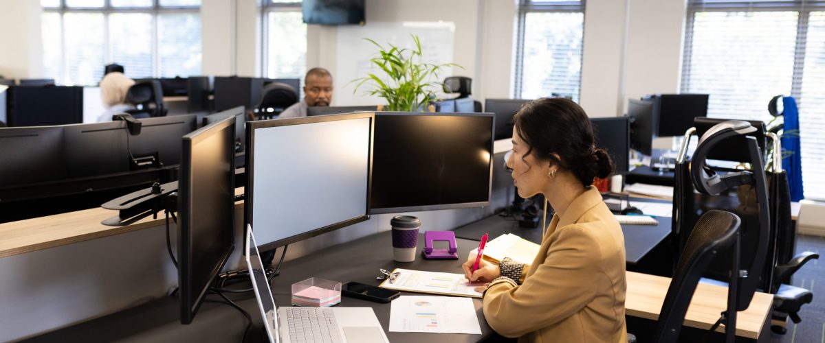 Asian woman sitting at desk and working on computer with copy space in office. Business, corporation, cooperation and working in office concept.