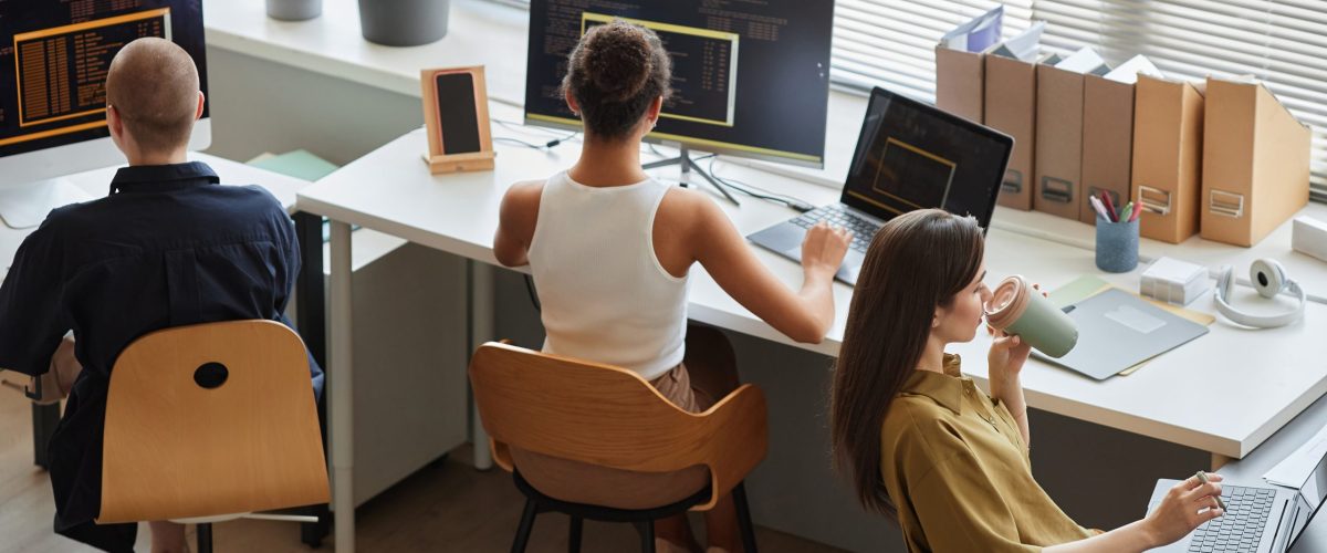 Back view at all female business team working on IT project in office, copy space